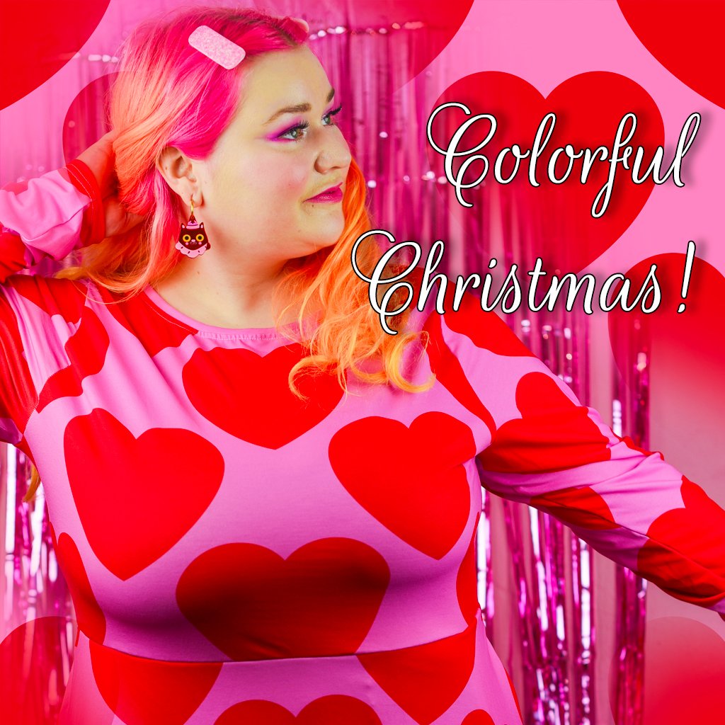 Woman in a SHALMIAK midi dress with big red hearts on pink. Text: Colorful Christmas!